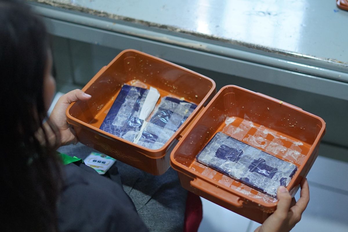 Pengunjung perempuan berinisial SA (39) diamankan petugas beserta barang bukti dua wadah nasi jagung yang dimodifikasi untuk menyelundupkan ponsel di Lapas Kelas I Surabaya, Kamis (22/10/2026) (KOMPAS.com/JACK ROBBY DAMARJATI)